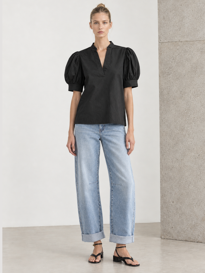 omen's black short-sleeve puff sleeve blouse with a split v-neckline and structured poplin finish, styled casually with white linen pants
