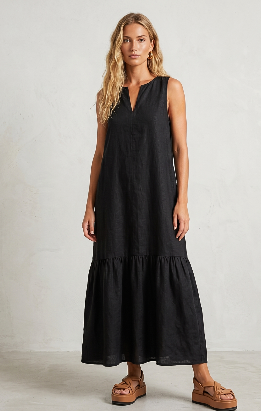 Woman wearing a black sleeveless dress with a plain background