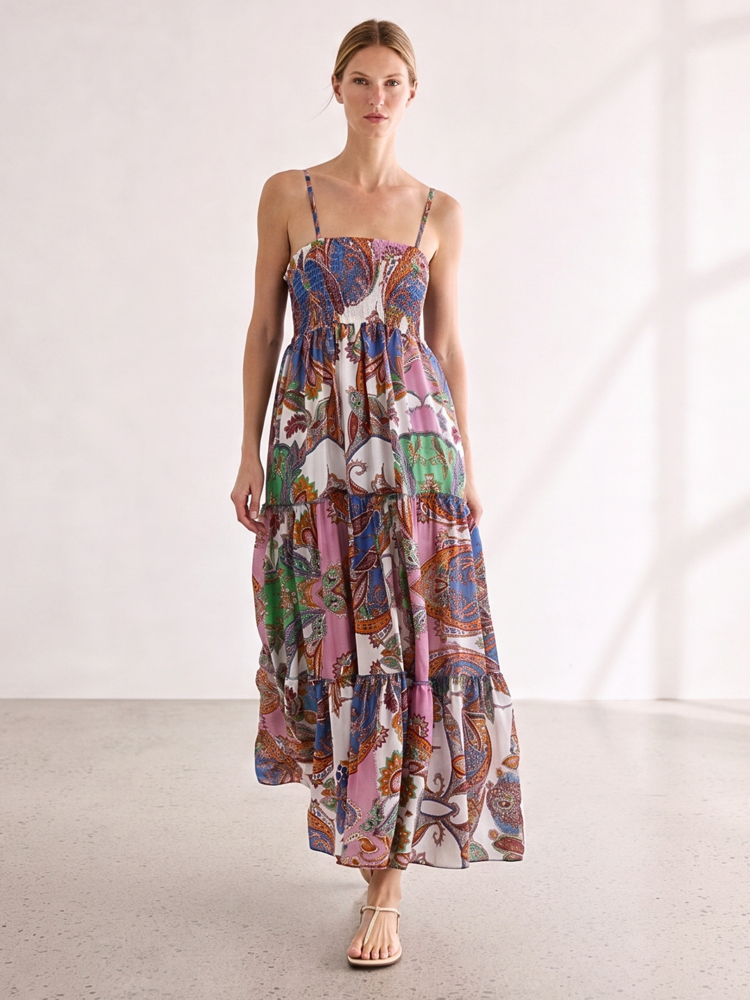 Woman wearing a colorful patterned dress against a neutral backgroun