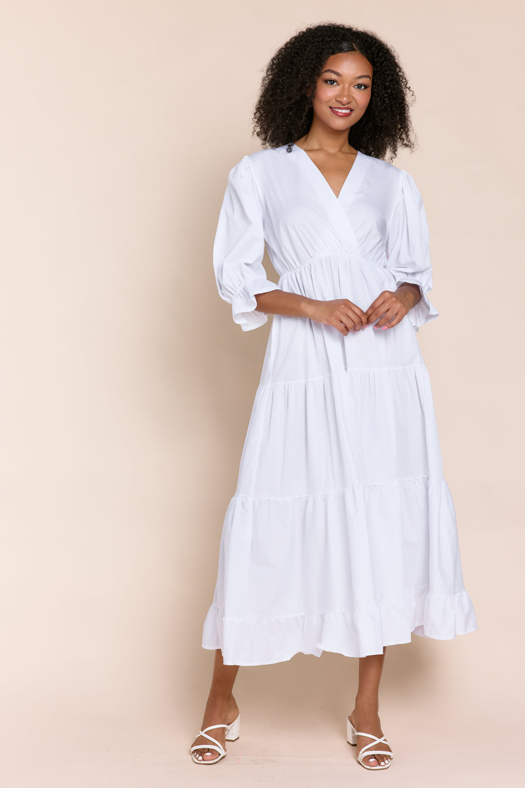 Woman wearing a white dress against a beige background