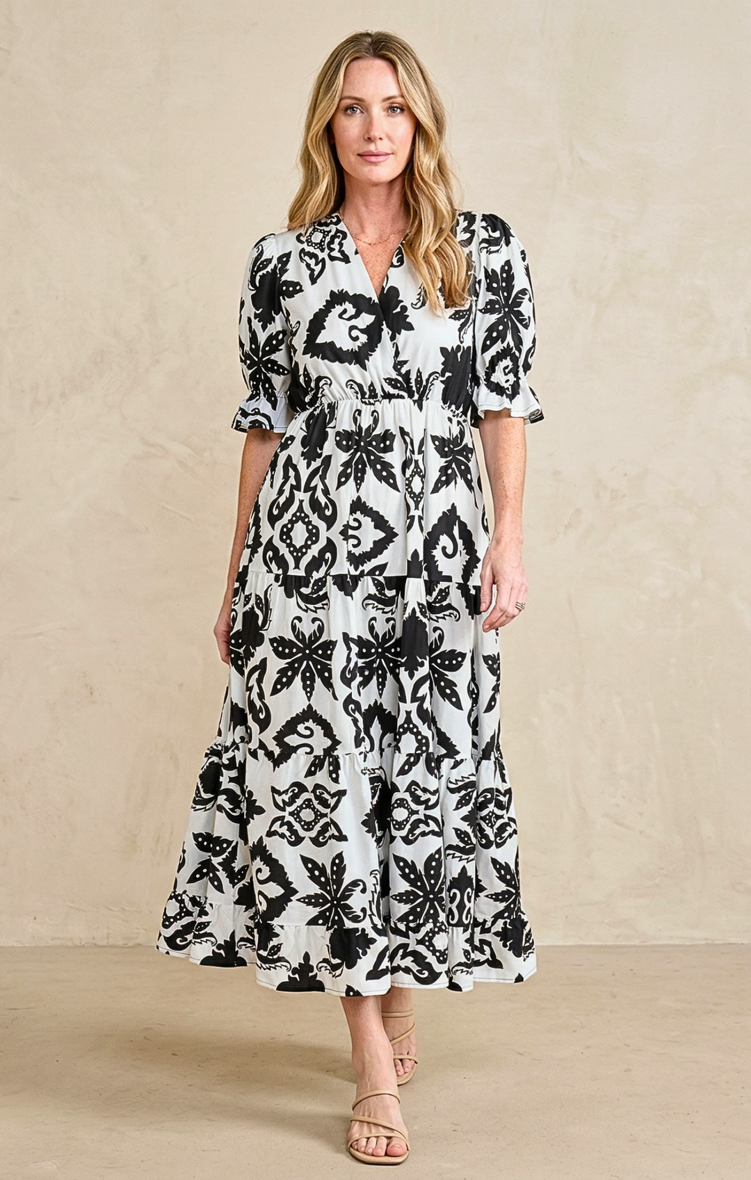 Woman wearing a black and white floral dress against a beige background
