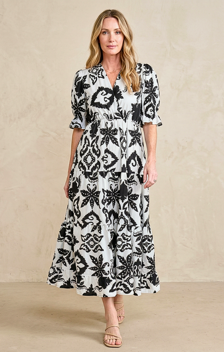 Woman wearing a black and white floral dress against a beige background