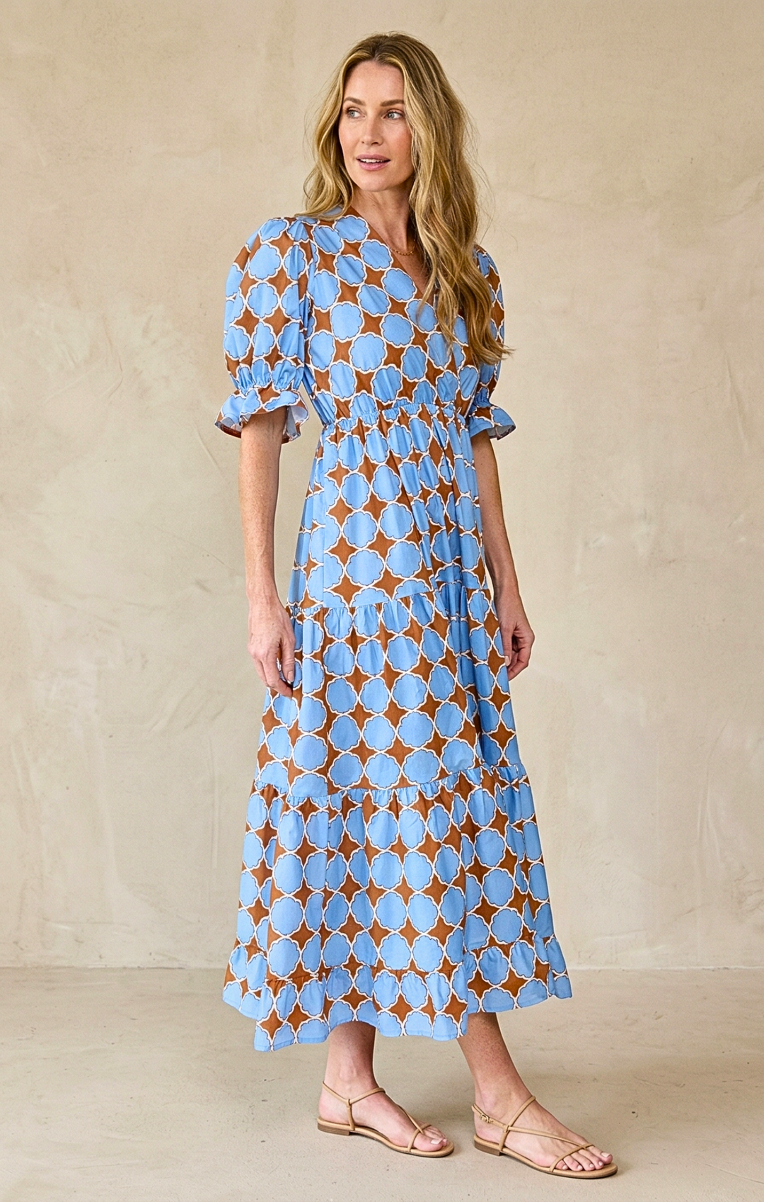 Woman wearing a blue and brown patterned dress against a beige background