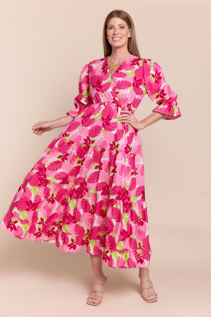 A woman modeling a red and white floral dress with 3/4 sleeves and a V-neck.