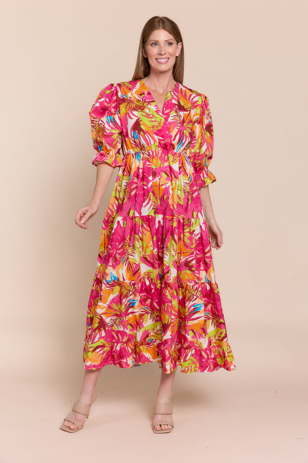 A woman modeling a red and white floral dress with 3/4 sleeves and a V-neck.