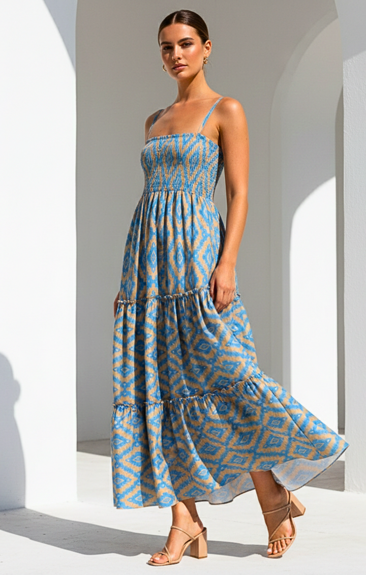 Woman wearing a blue and beige patterned dress standing against a white architectural background