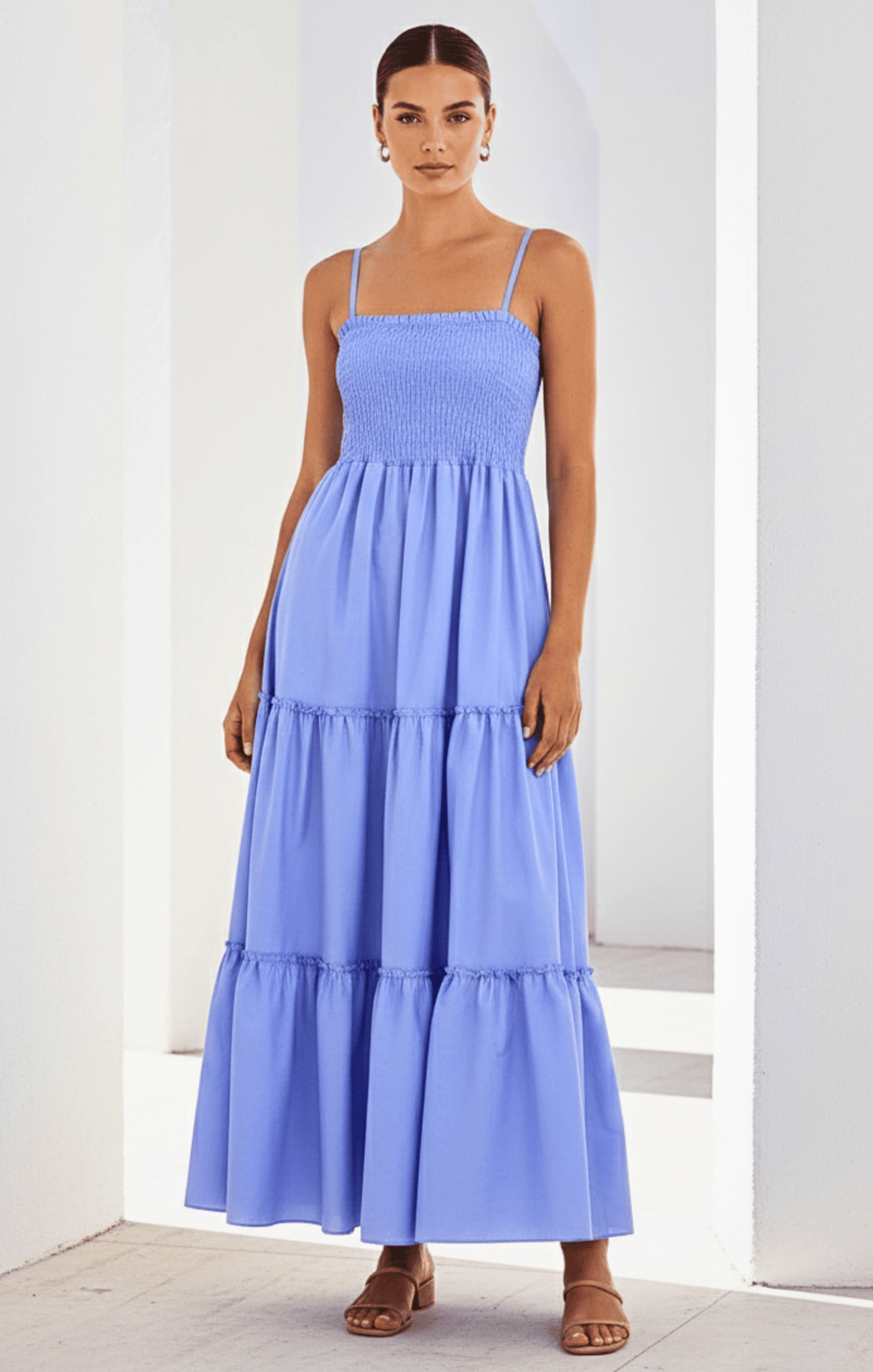 Woman wearing a light blue tiered dress against a white background
