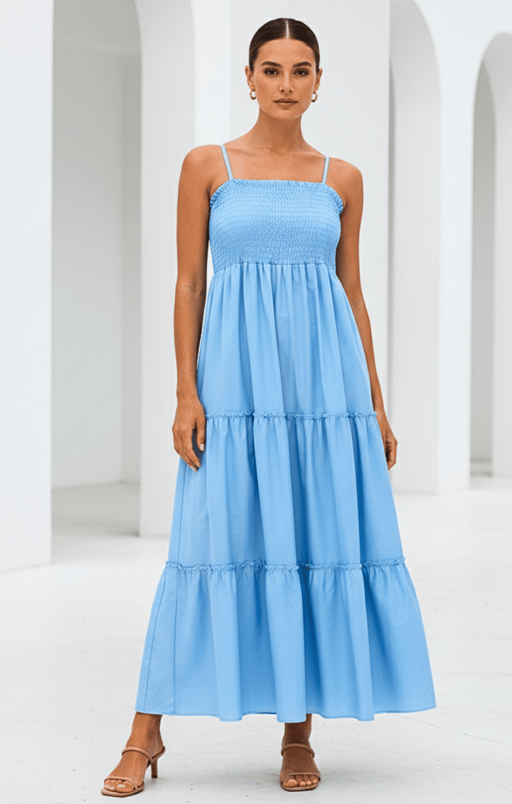Woman wearing a light blue tiered dress against a white architectural background