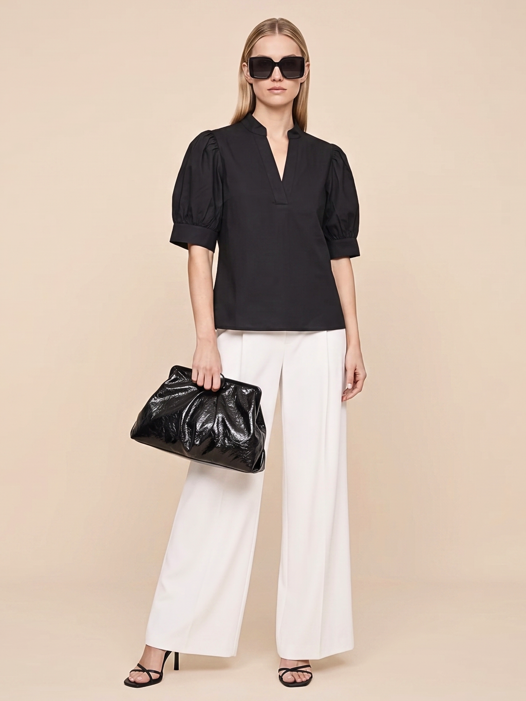 omen's black short-sleeve puff sleeve blouse with a split v-neckline and structured poplin finish, styled casually with white linen pants