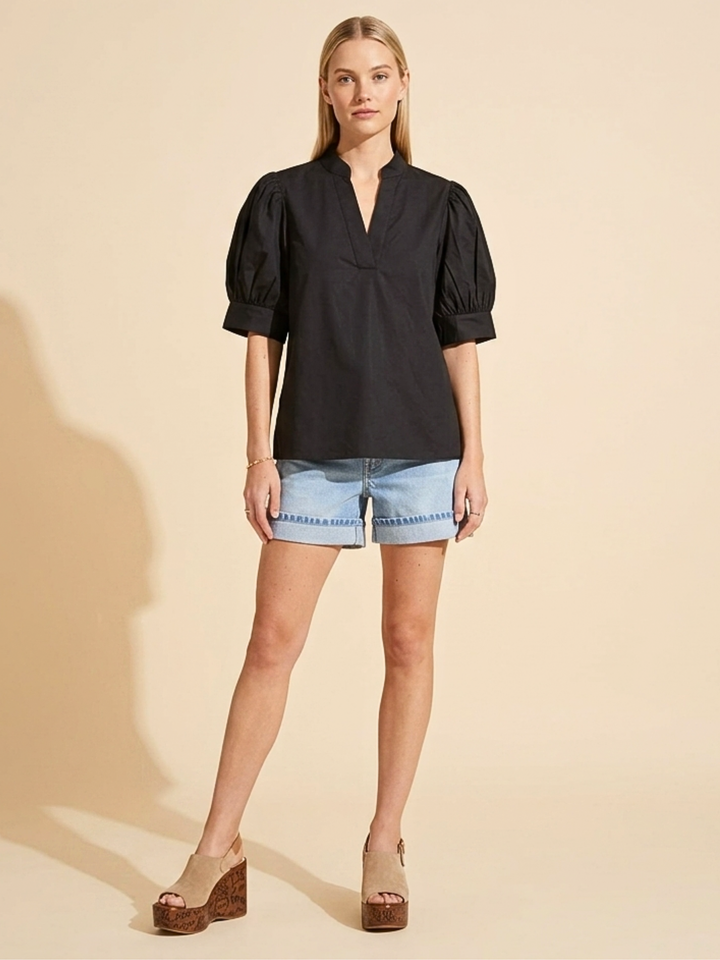 omen's black short-sleeve puff sleeve blouse with a split v-neckline and structured poplin finish, styled casually with denim shorts."