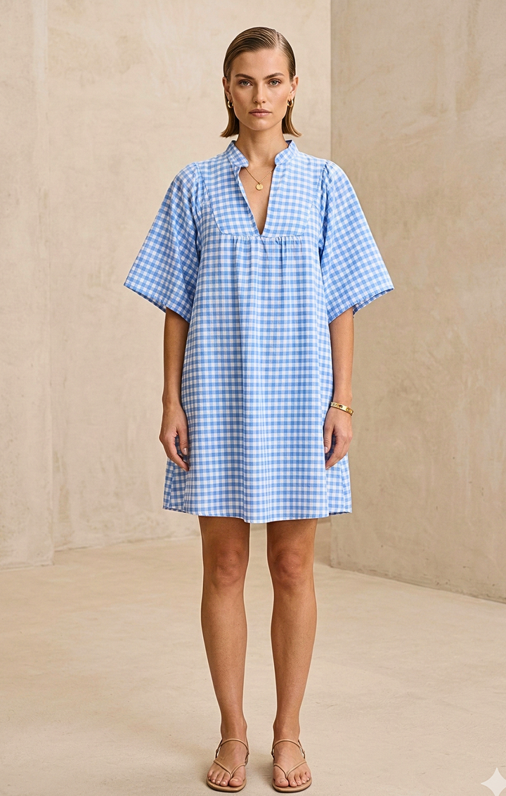 Woman wearing a blue checkered dress against a beige background