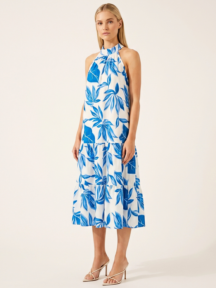 Woman wearing a blue and white leaf-patterned dress on a beige background