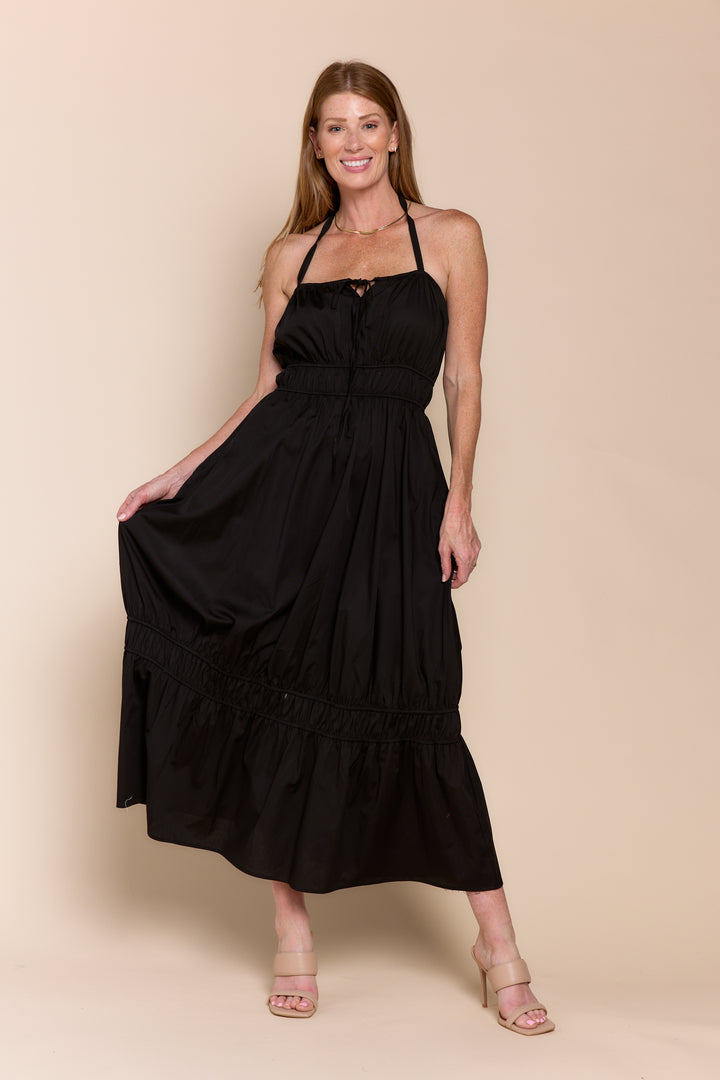 Woman wearing a black halter neck dress on a beige background