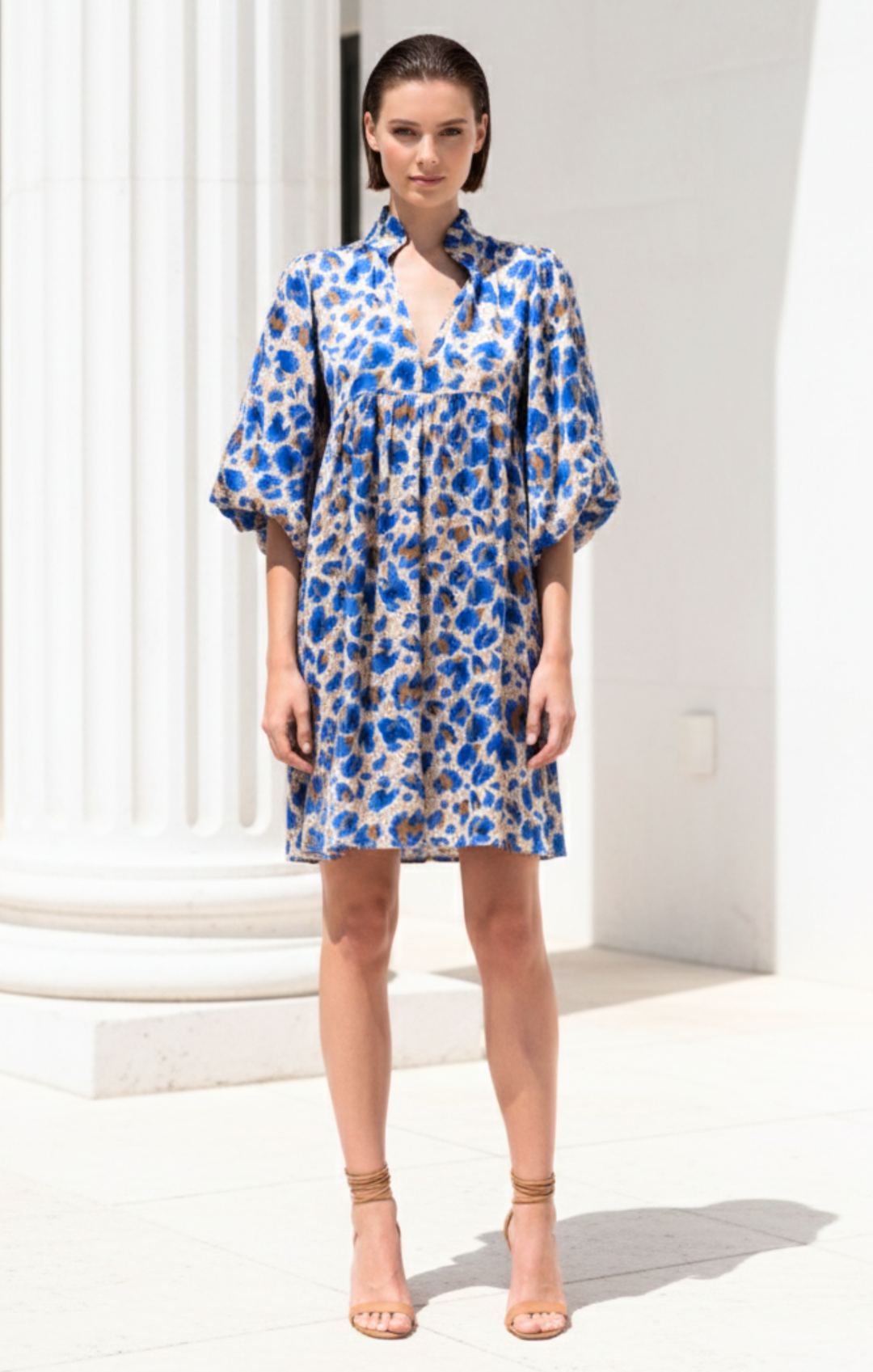 Woman wearing a blue floral dress in a minimal white setting