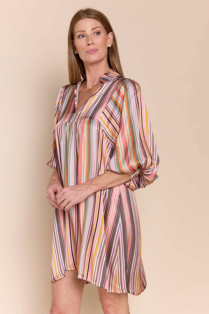 Woman wearing a multicolored striped dress against a beige background