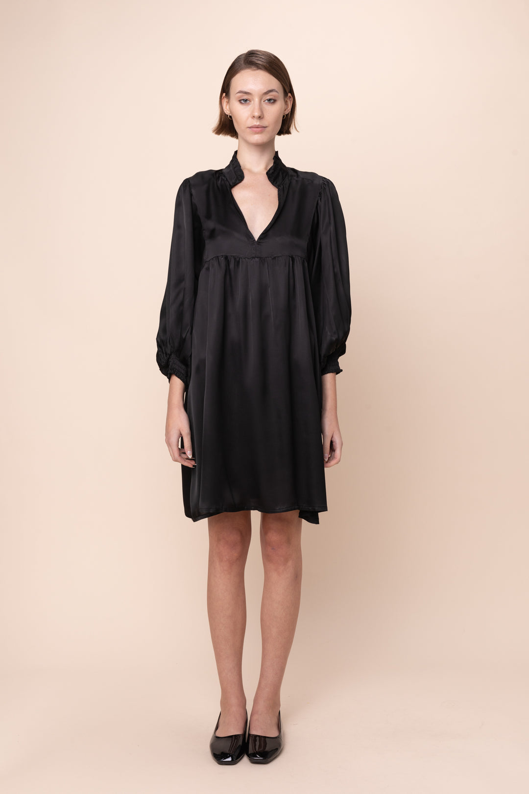 Woman wearing a black dress on a beige background