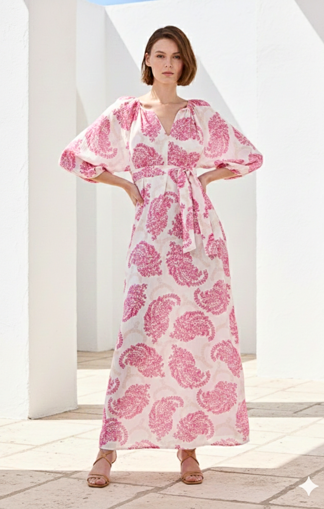 Woman wearing a pink and white patterned dress standing in a bright outdoor setting.