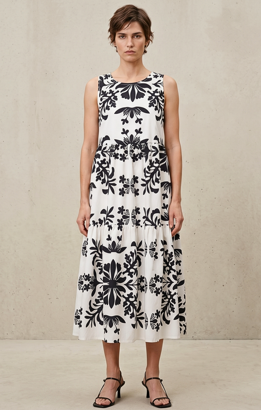 Woman wearing a sleeveless dress with black floral pattern on a neutral background