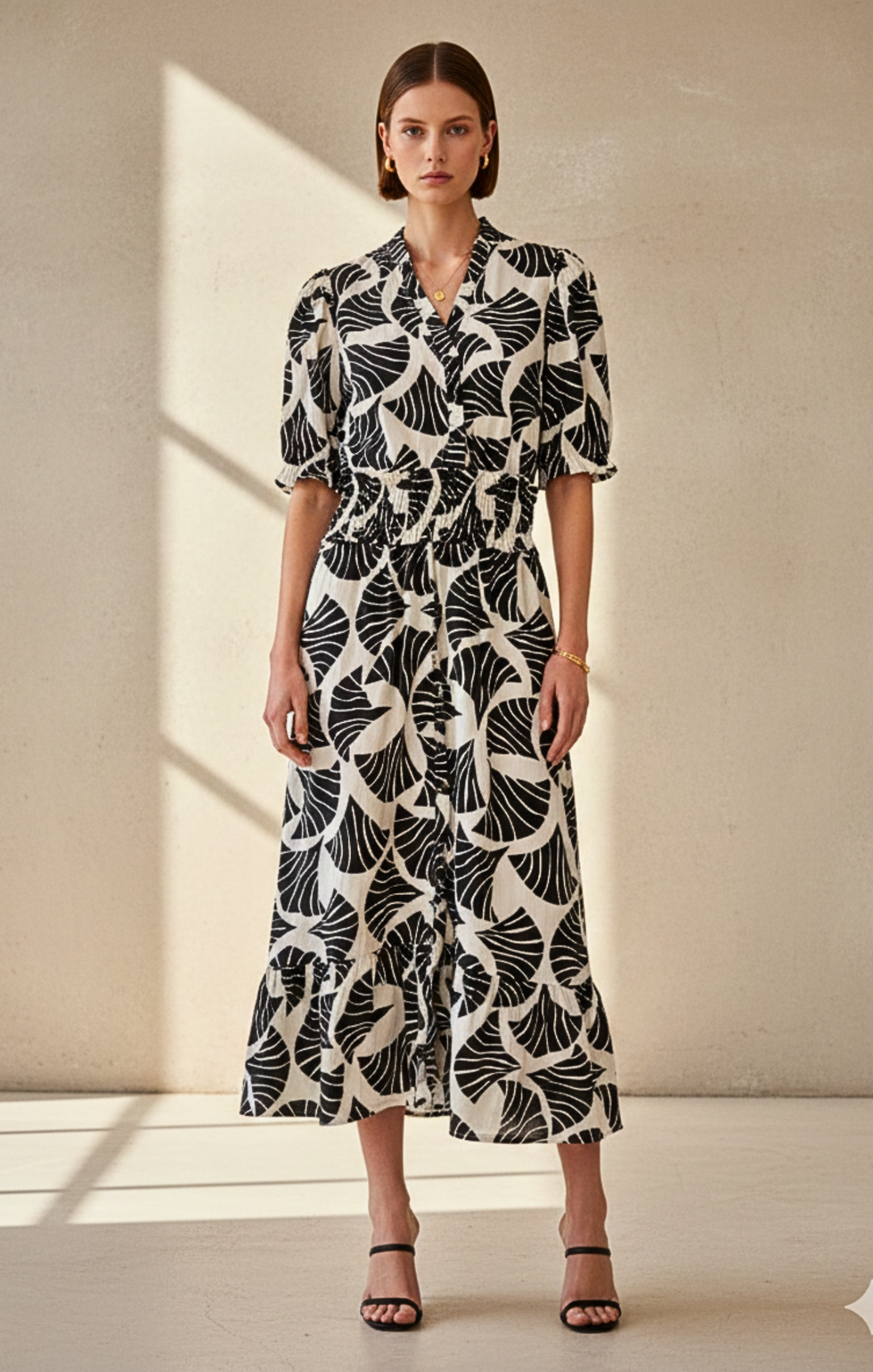 Woman wearing a black and white patterned dress standing against a neutral background