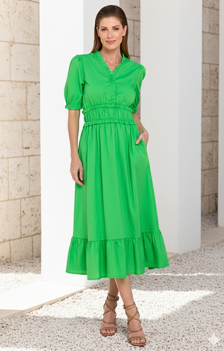 Woman wearing a green dress standing in front of classical architecture.