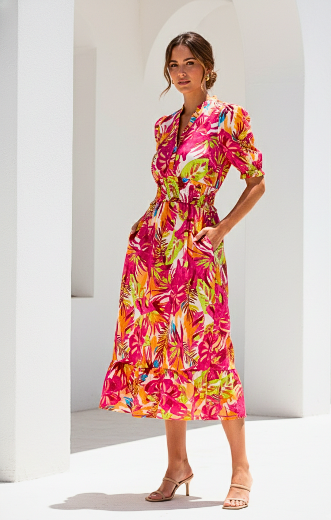 Woman wearing a colorful floral dress against a white architectural background