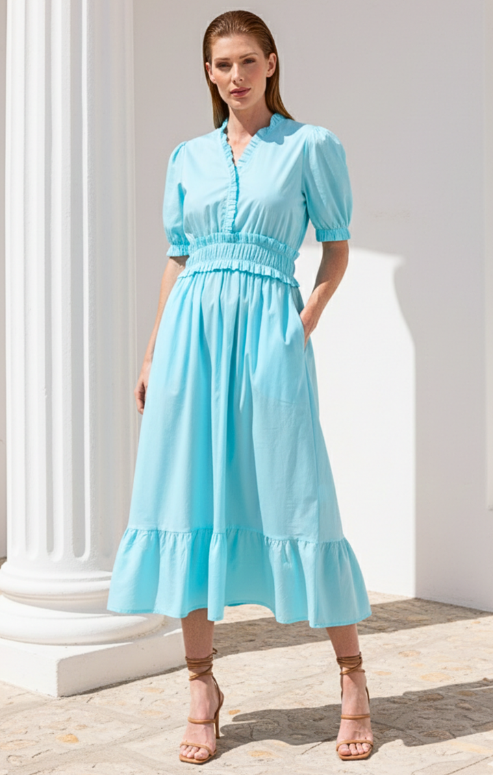 Woman wearing a light blue dress standing against a white architectural background