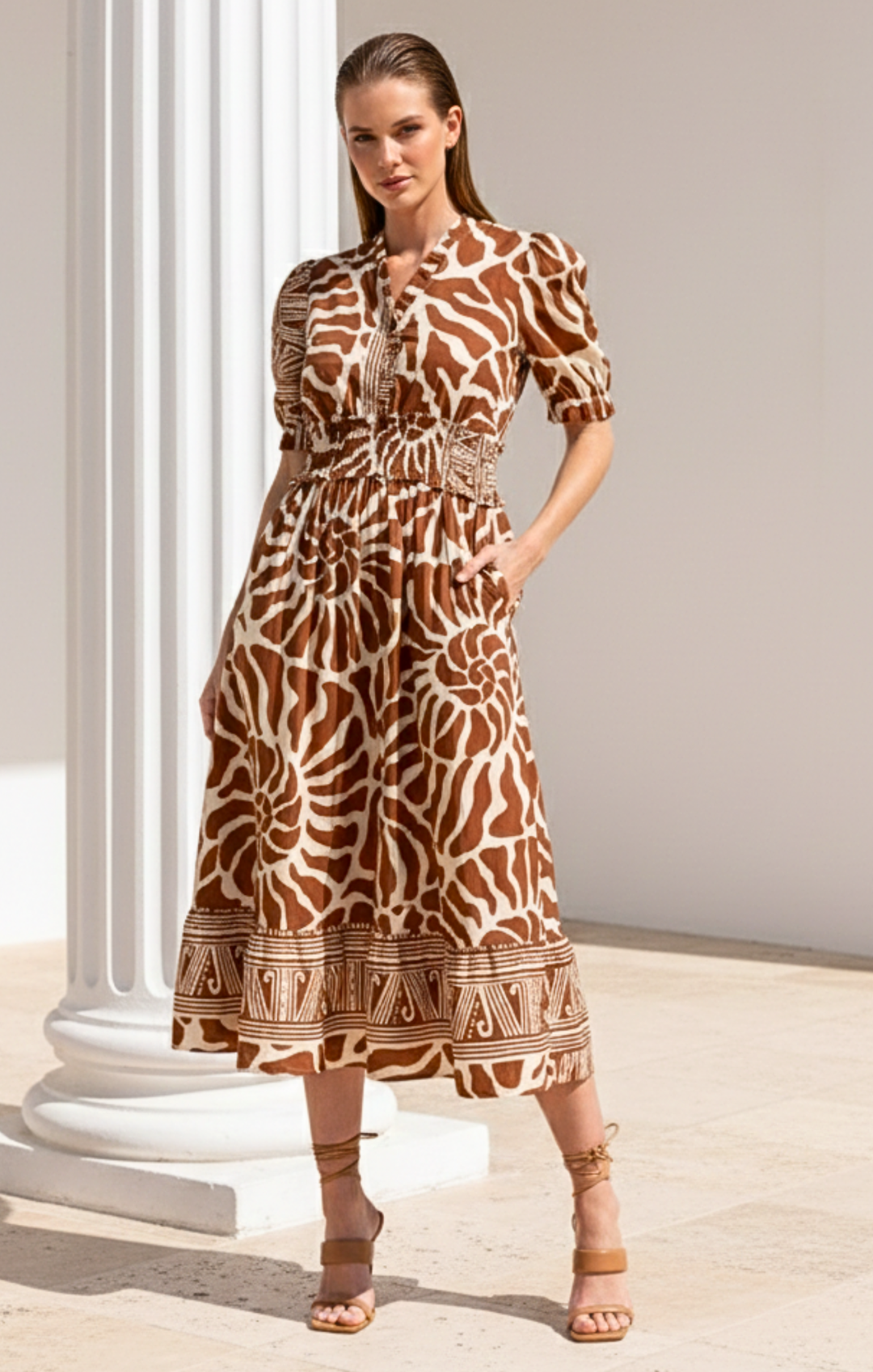 Woman wearing a patterned dress standing against a neutral background