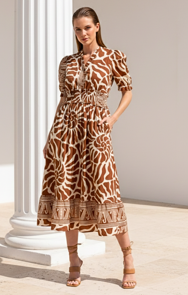 Woman wearing a patterned dress standing against a neutral background