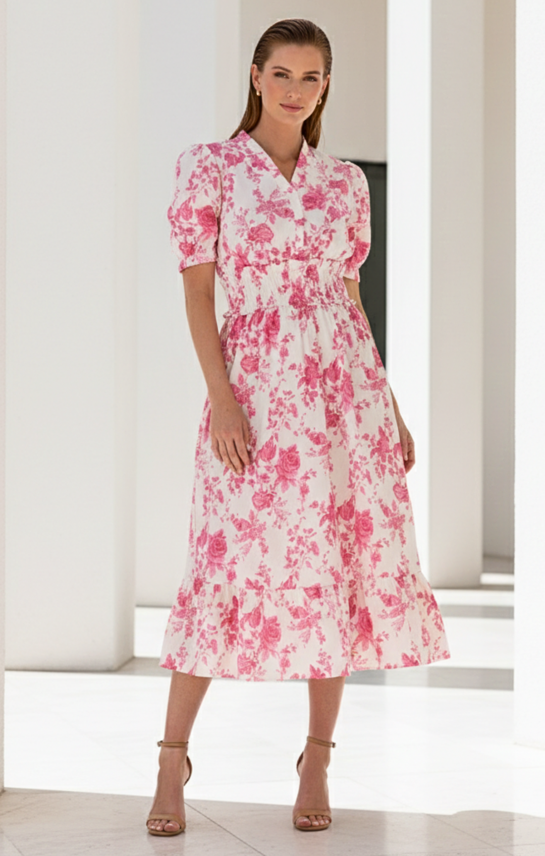 Woman wearing a pink floral dress in a minimal indoor setting