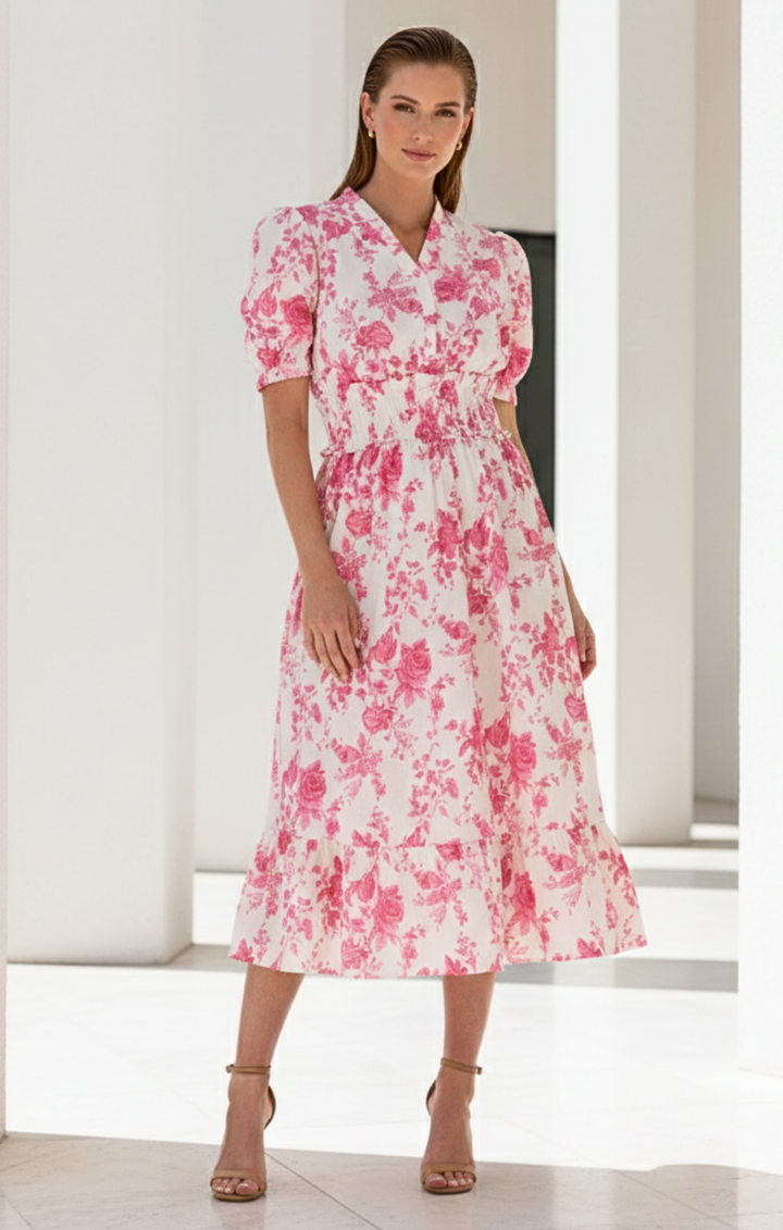 Woman wearing a pink floral dress in a minimal indoor setting