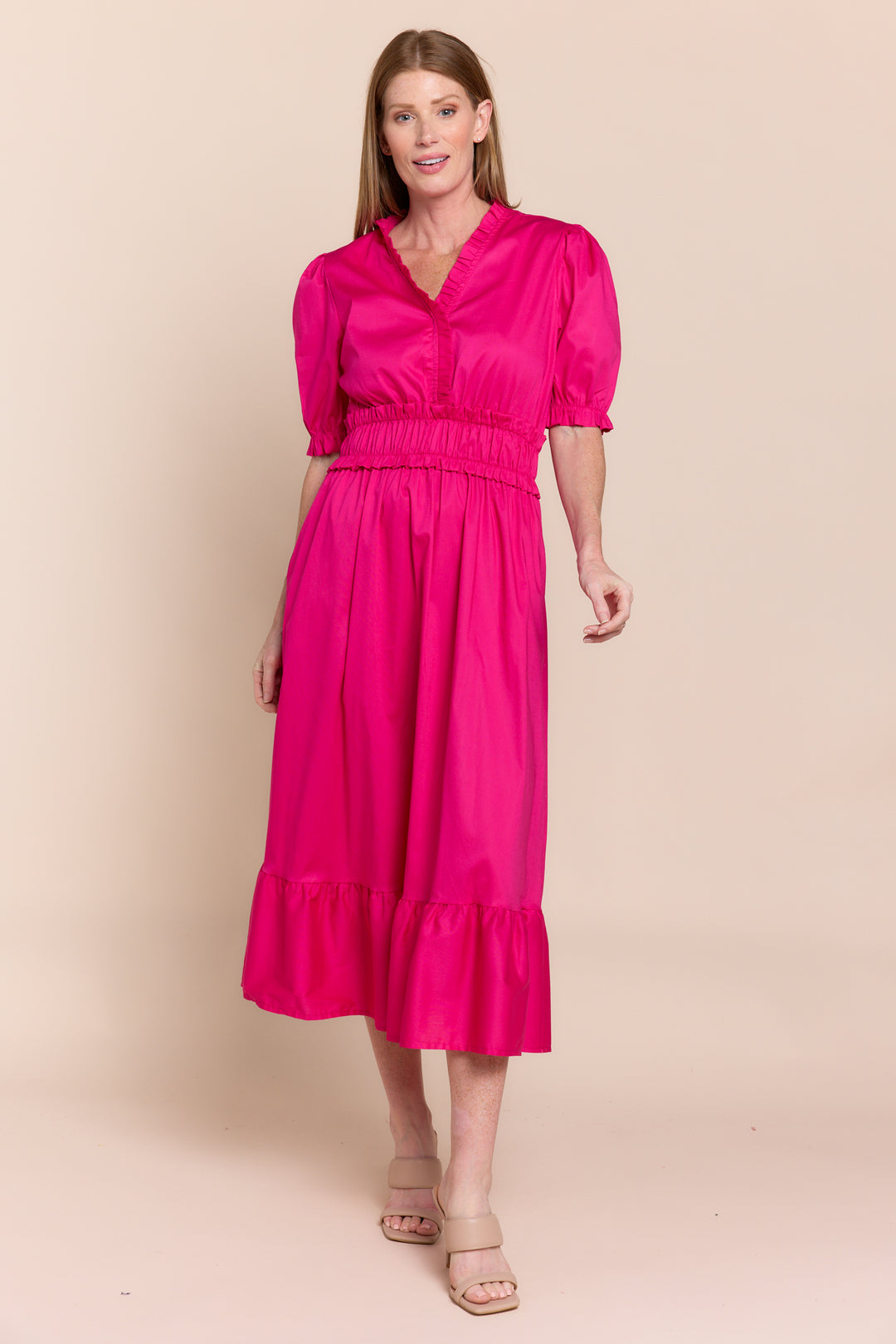 Woman wearing a bright pink dress against a beige background