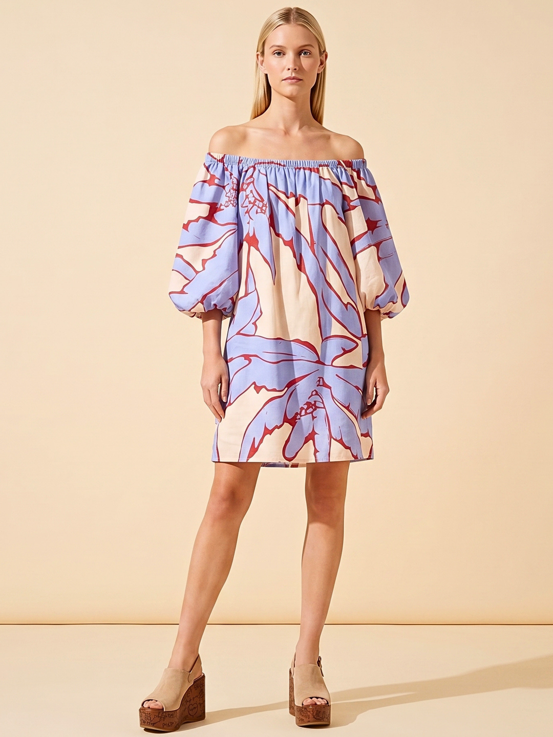 Model wearing an off-the-shoulder cotton voile mini dress with a blue and red abstract botanical print, featuring voluminous balloon sleeves and a relaxed, breezy fit perfect for summer vacation wear."