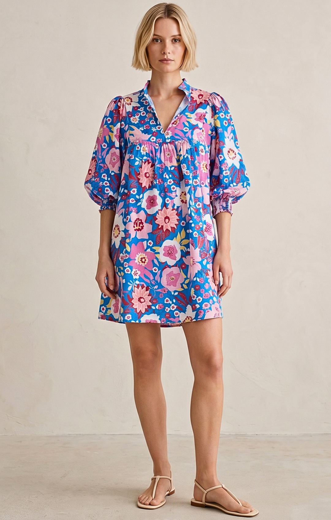 Woman wearing a colorful floral dress against a plain background