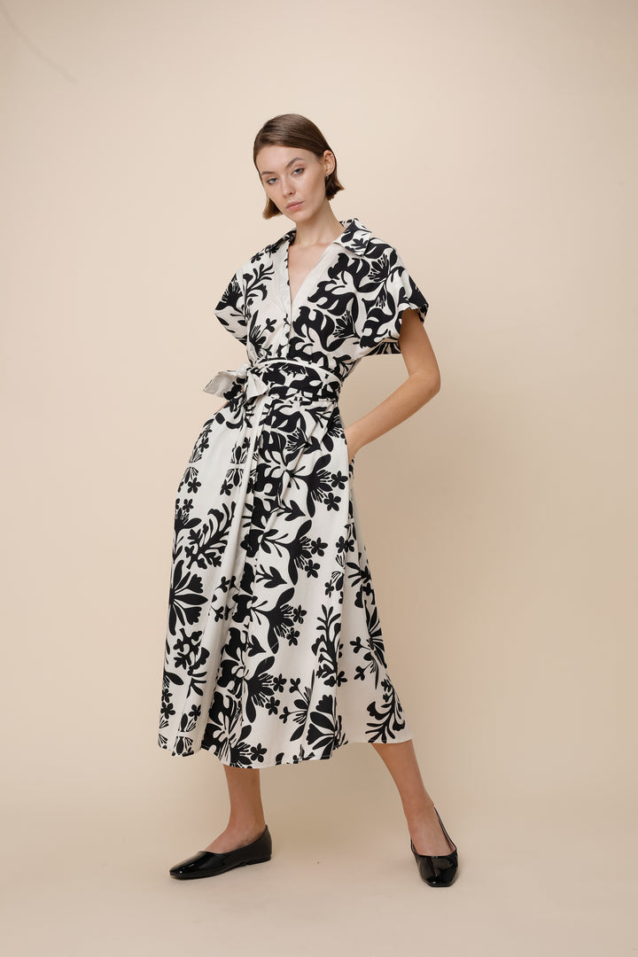 Woman wearing a black and white floral dress on a beige background
