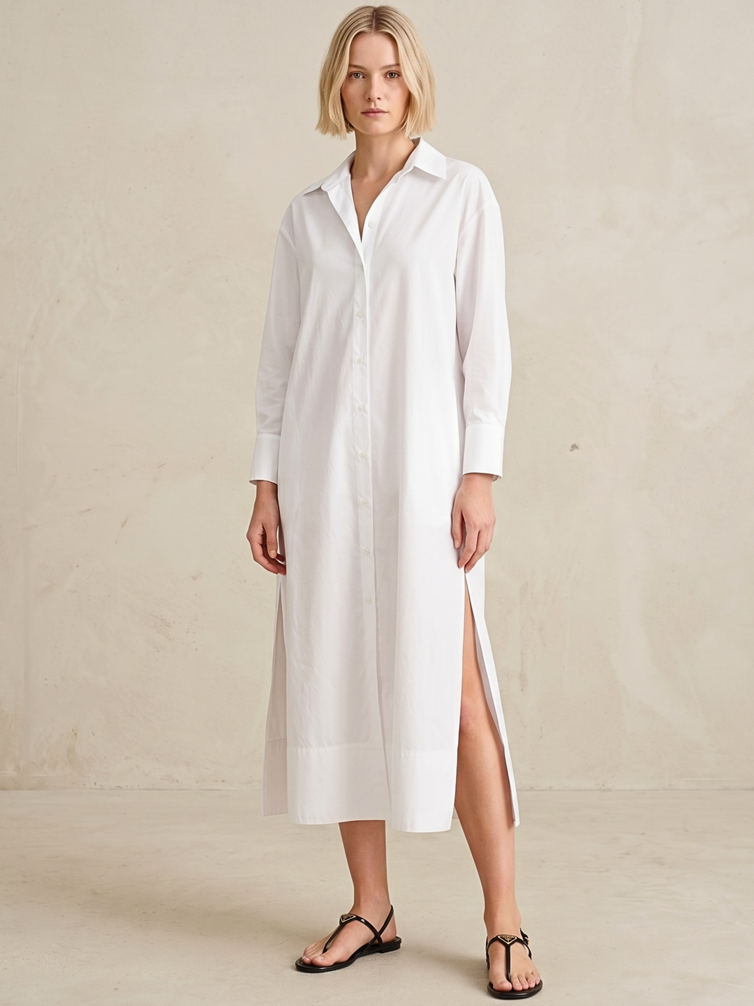 Woman wearing a white shirt dress against a plain background