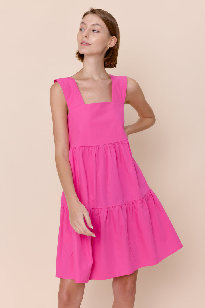 Woman wearing a bright pink dress against a beige background
