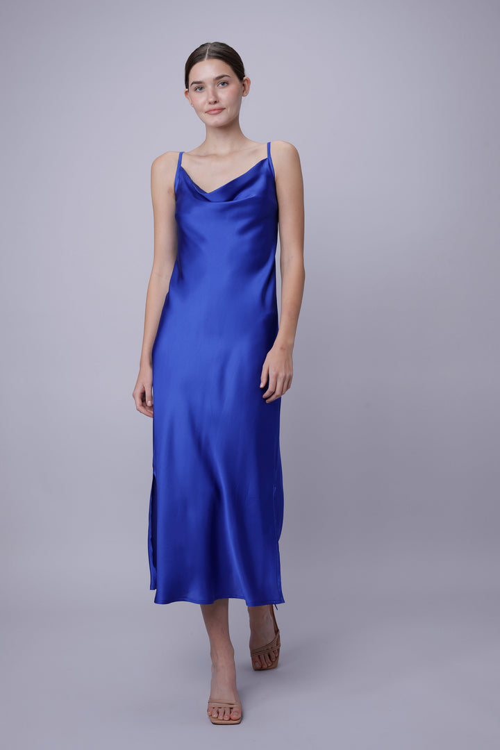 Woman wearing a blue satin slip dress on a gray background