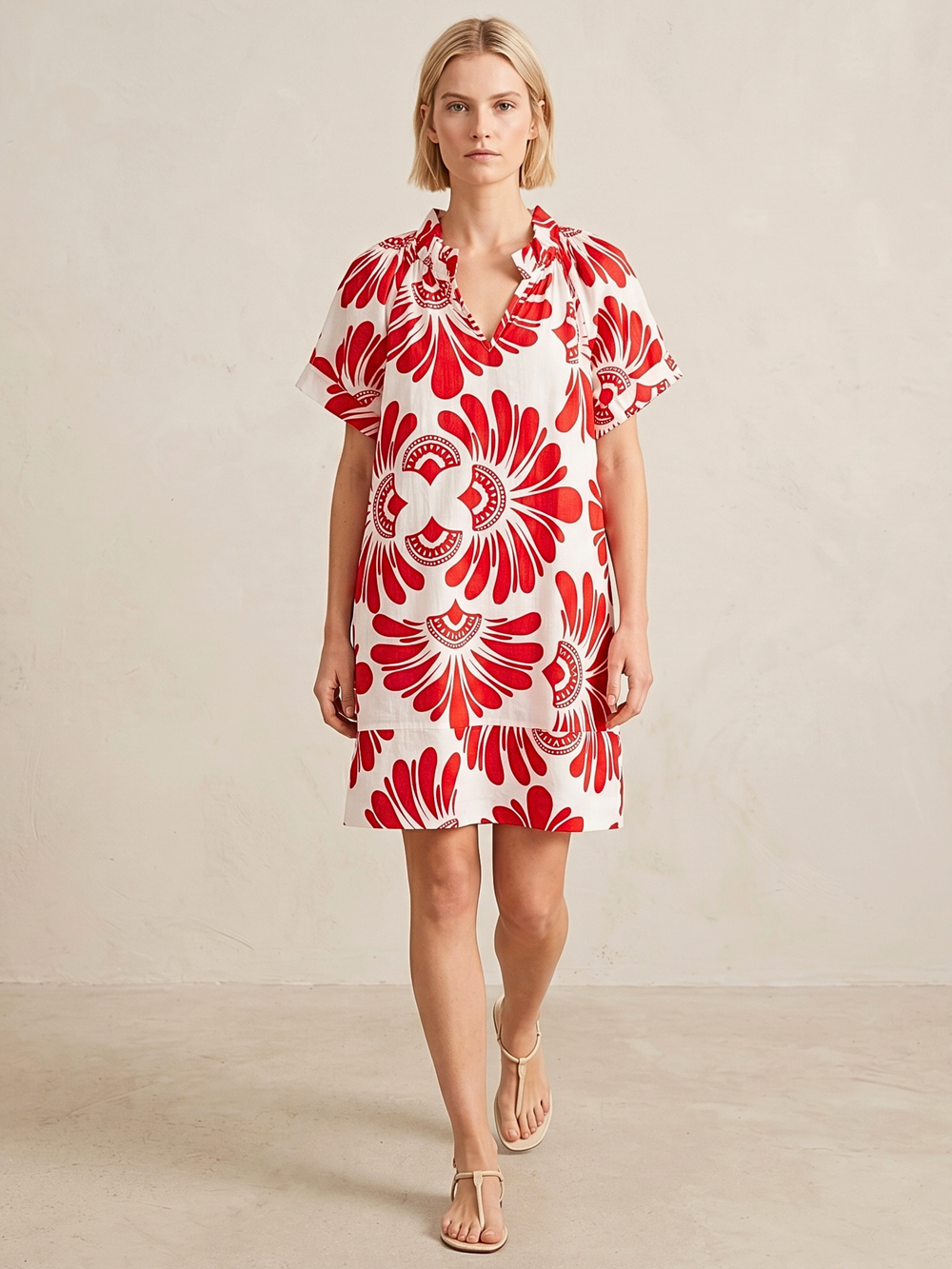 Woman wearing a red and white floral dress against a plain background