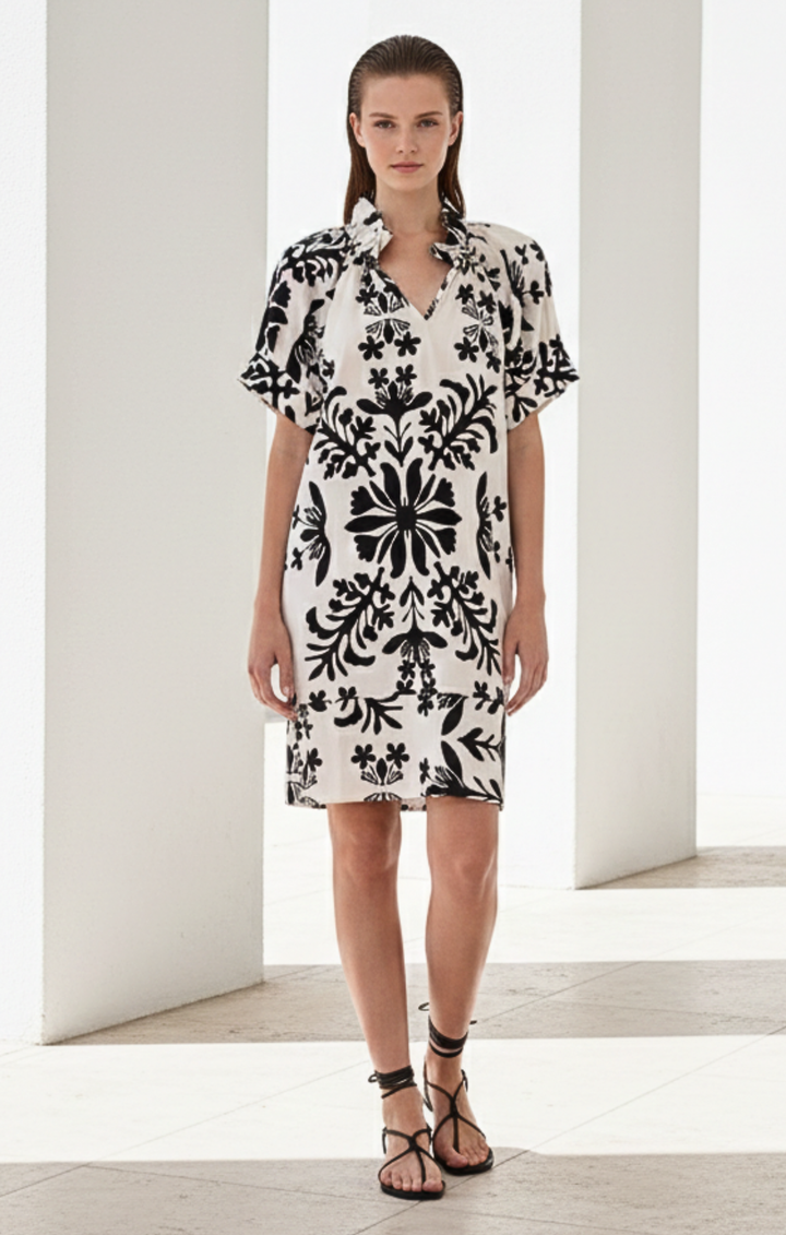 Woman wearing a black and white floral dress in a minimalistic setting