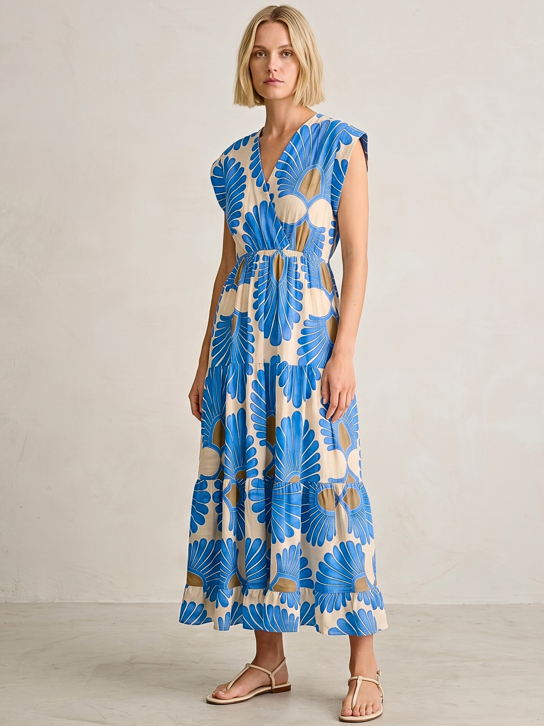 Woman wearing a blue and beige floral dress against a plain background