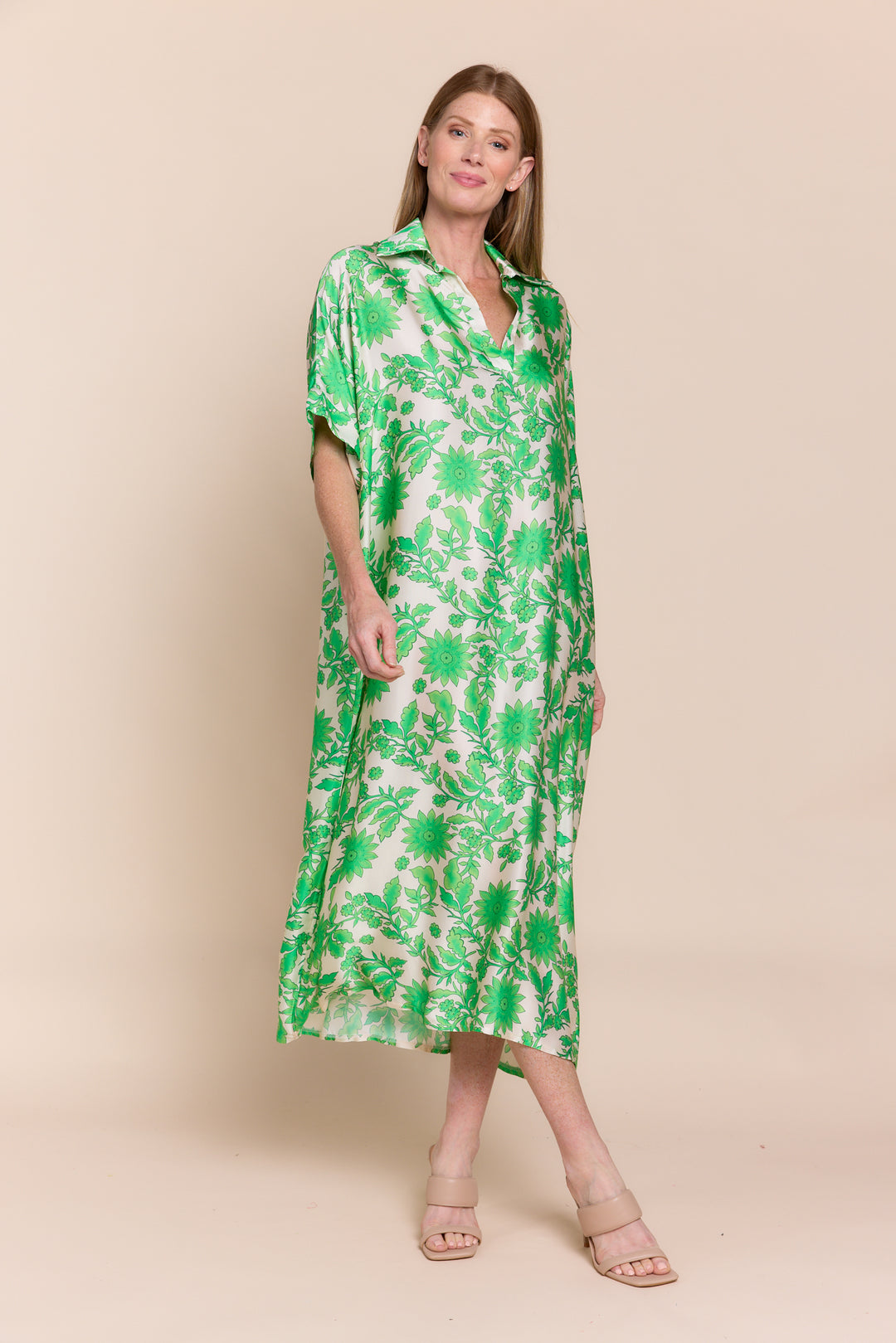 Woman wearing a green floral dress against a beige background