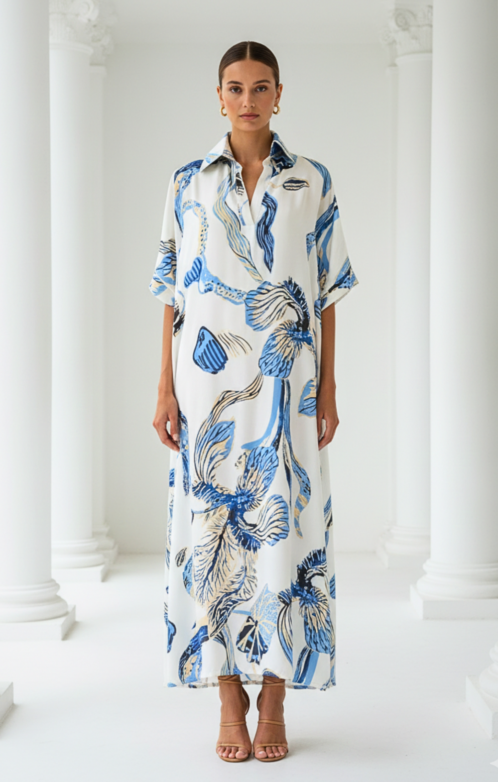 Woman wearing a long, patterned dress standing against a white background