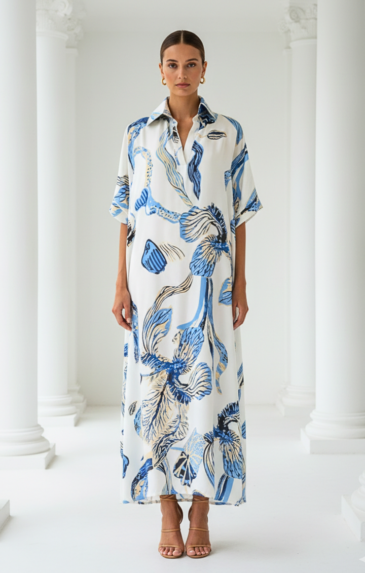 Woman wearing a long, patterned dress standing against a white background