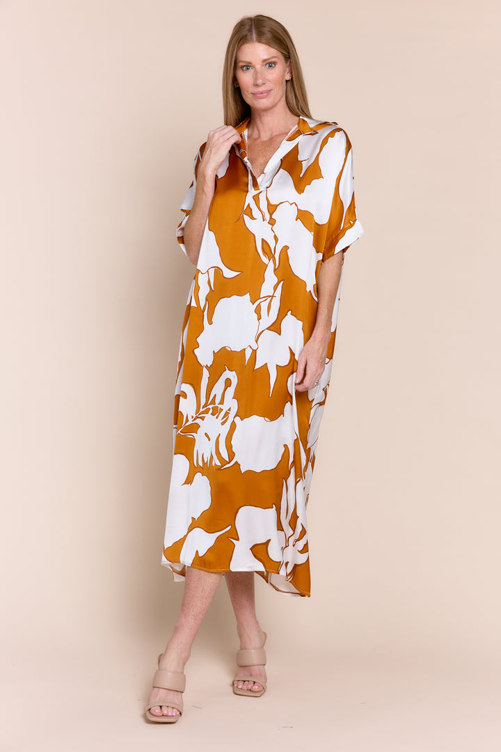 Woman wearing a mustard yellow dress with white floral pattern on a beige background
