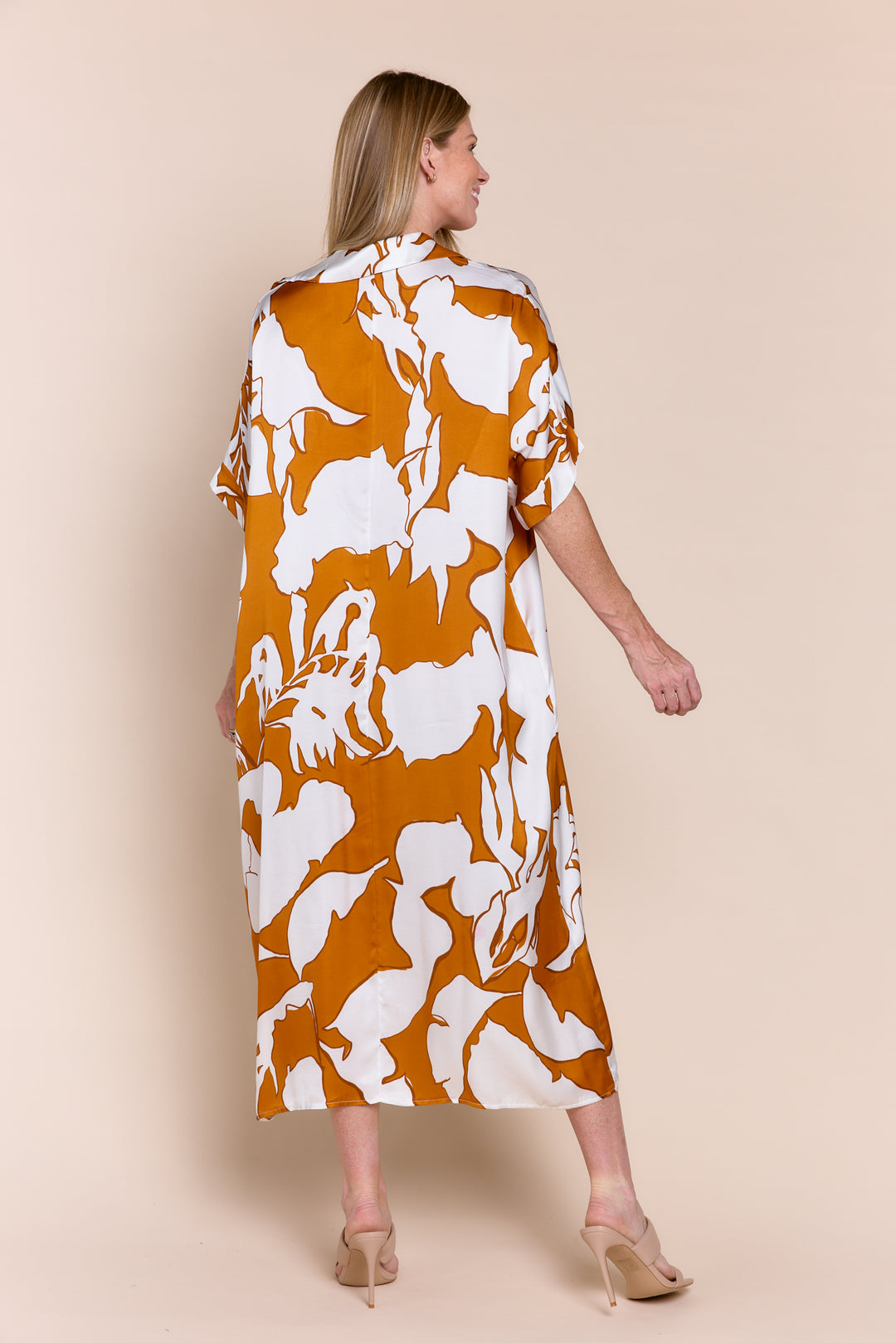 Woman wearing a floral dress with orange and white pattern on a beige background