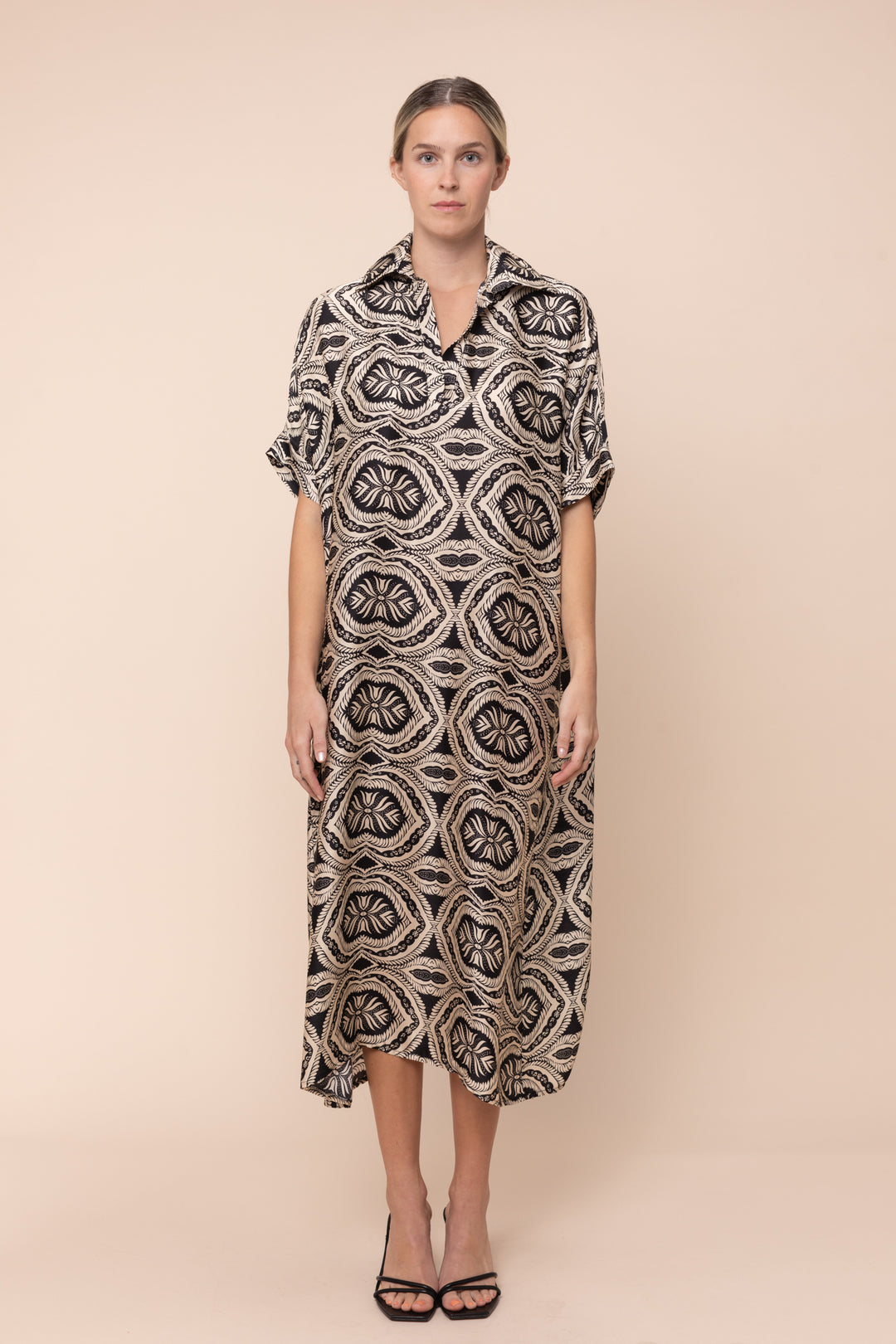 Woman wearing a patterned dress against a beige background