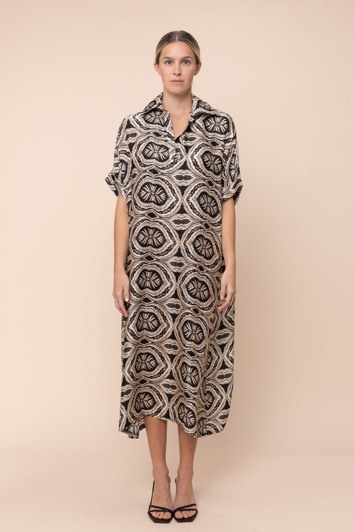 Woman wearing a patterned dress against a beige background