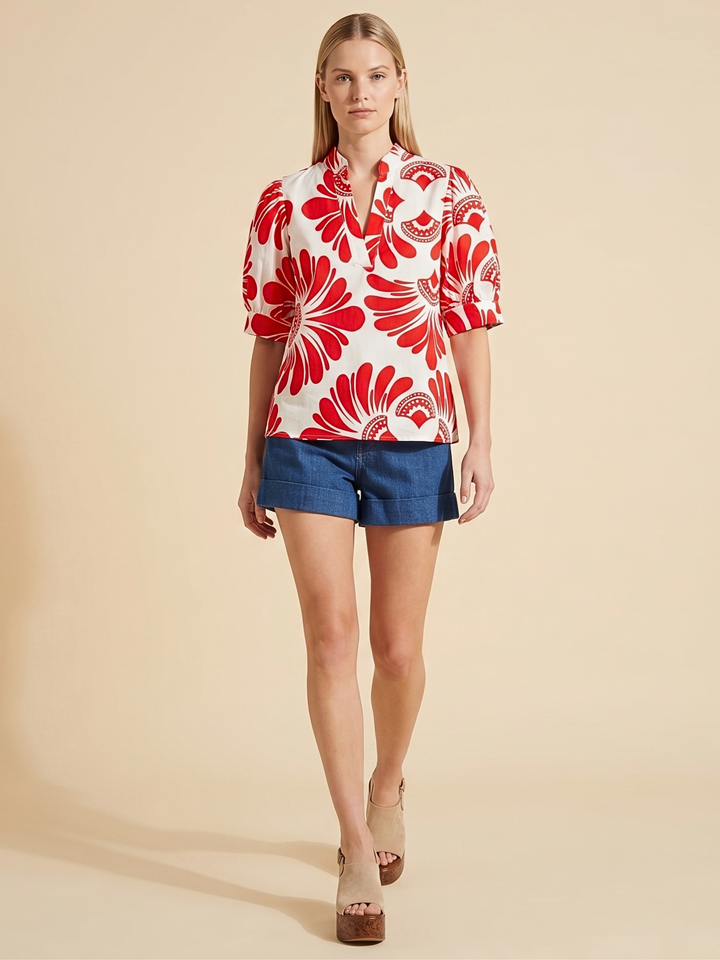 Women's short-sleeve button-up shirt in white with a bold red abstract floral print, viewed from the back.