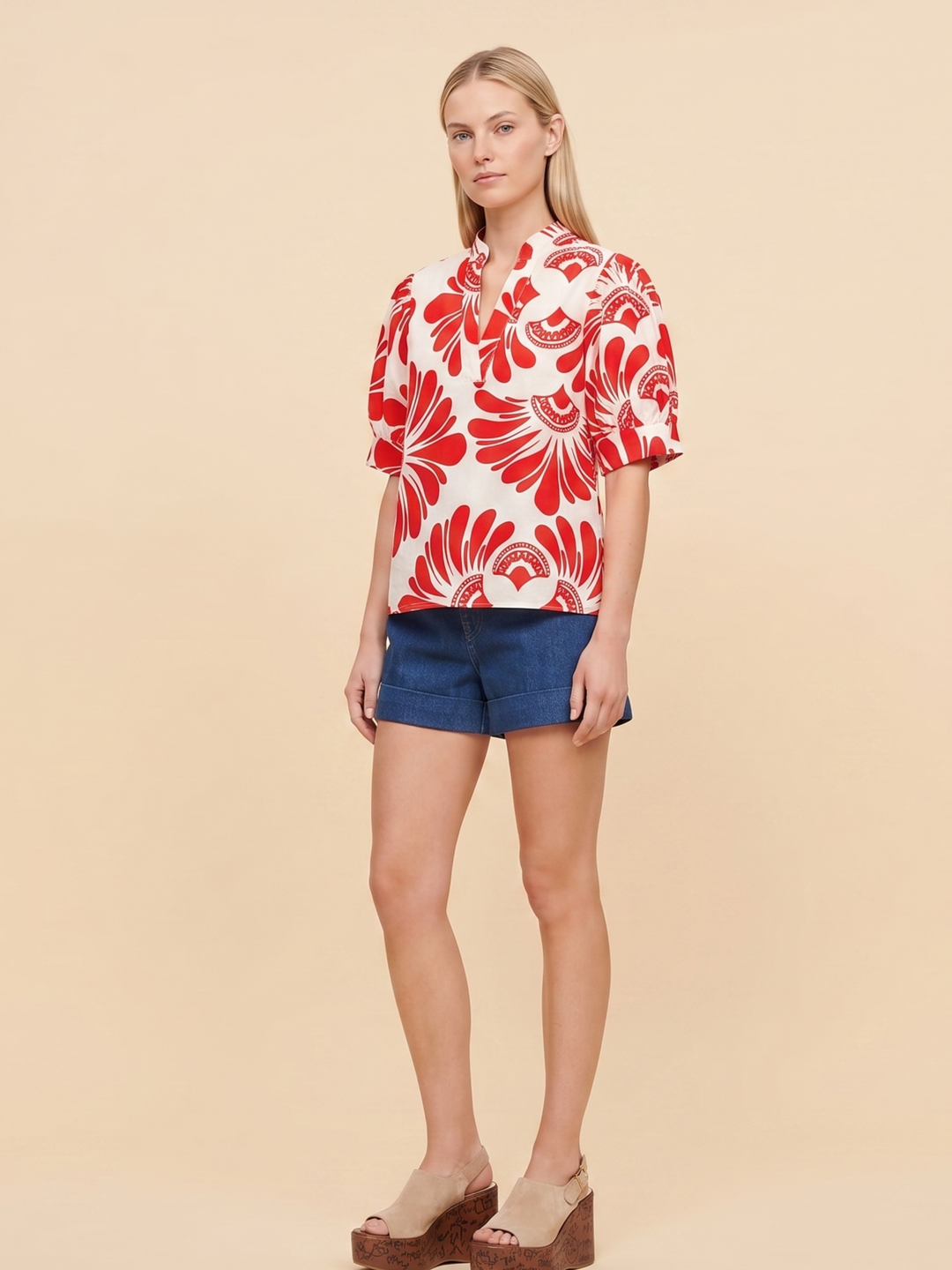 Women's short-sleeve button-up shirt in white with a bold red abstract floral print, viewed from the back.