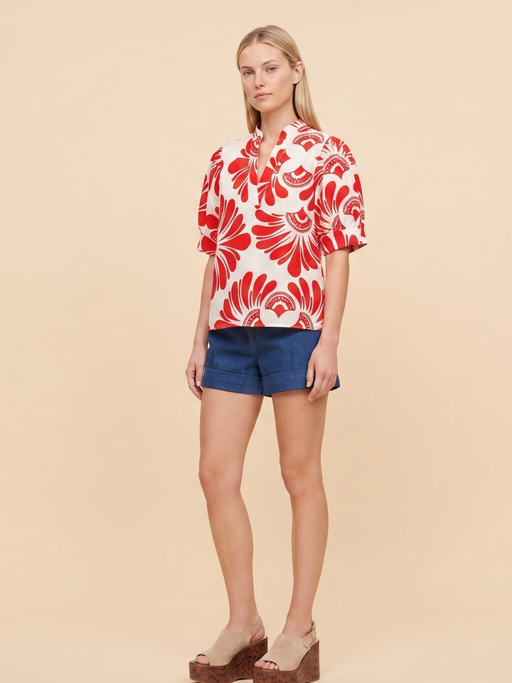 Women's short-sleeve button-up shirt in white with a bold red abstract floral print, viewed from the back.